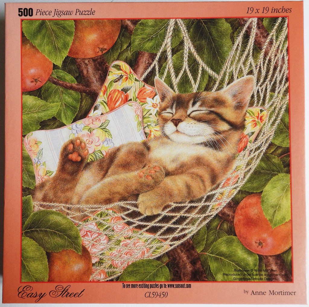 A ginger tabby kitten sleeping in a hammock nestled in an apple tree.