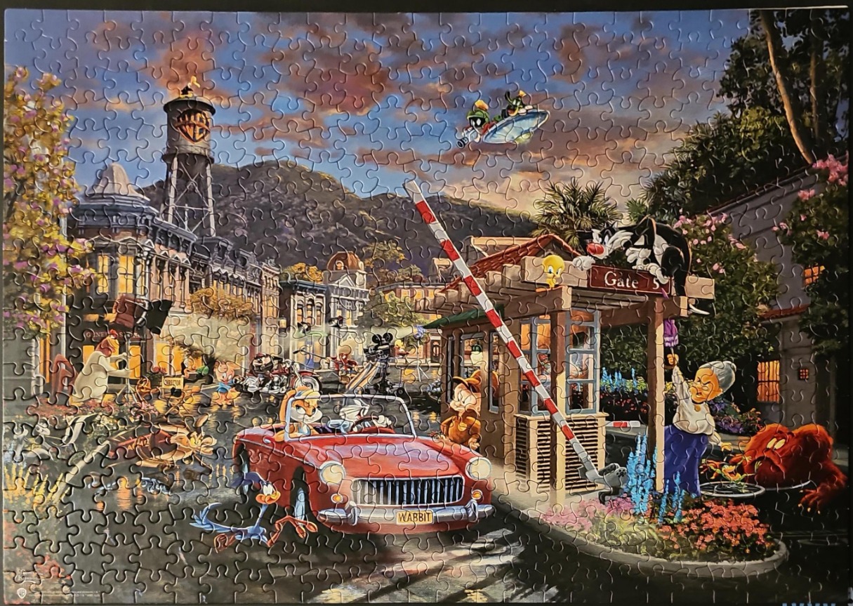 A whimsical illustration of various cartoon characters at a film studio gate at sunset.