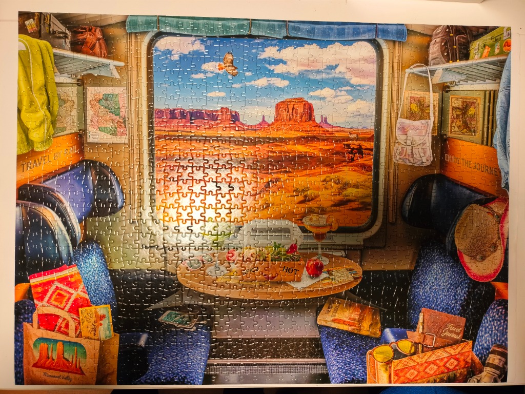 A view of Monument Valley through a train window with travel gear on the seats and table.