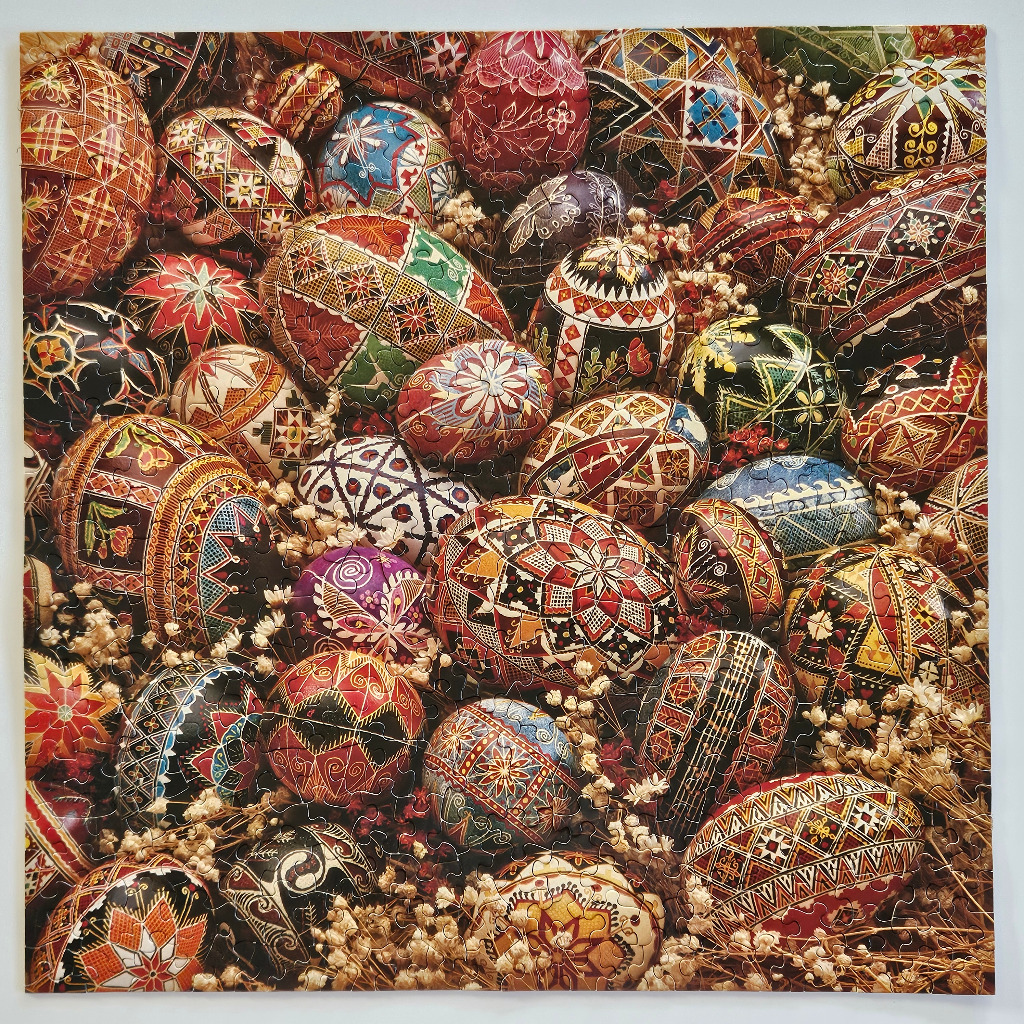 A collection of intricately decorated Easter eggs nestled among sprigs of dried flowers.