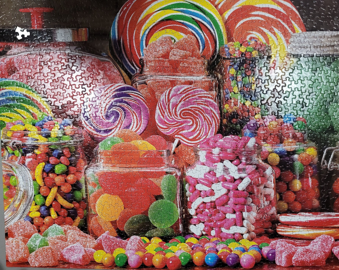 A close-up view of glass jars overflowing with an assortment of colourful, vibrant candy and lollipops.