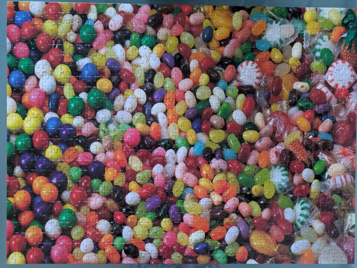 A dense, vibrant collection of multi-coloured jelly beans and wrapped candies.