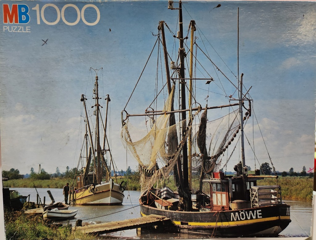 Two fishing boats moored in a calm river channel against a clear blue sky.