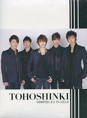 Studio portrait of five young men from the group Tohoshinki wearing black outfits against a white background.