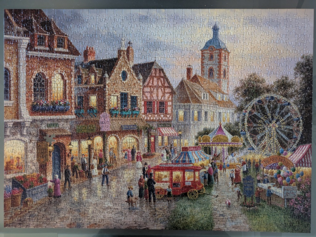 An illustration of a quaint European-style town square with a carnival featuring a carousel and ferris wheel at twilight.