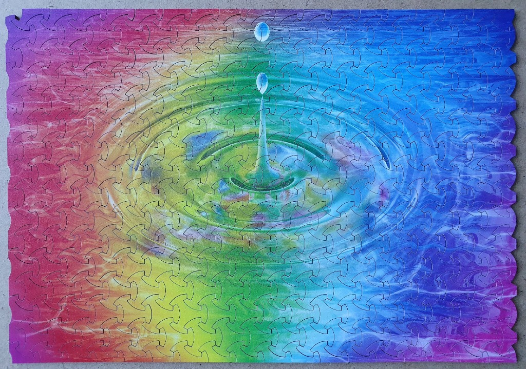 A water droplet falling into a liquid surface with a vibrant rainbow gradient background.