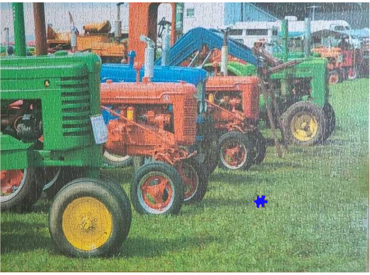 A row of vintage tractors parked in a field of grass.