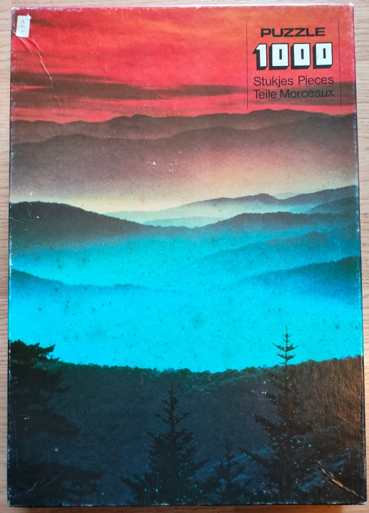 A panoramic landscape of mountain ridges fading into a bright sunset sky.
