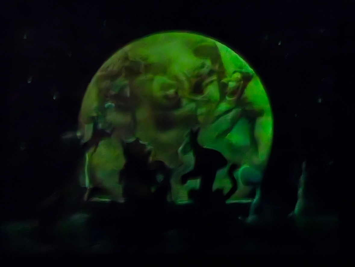 Green glowing planet with shadowy figures and starry sky.