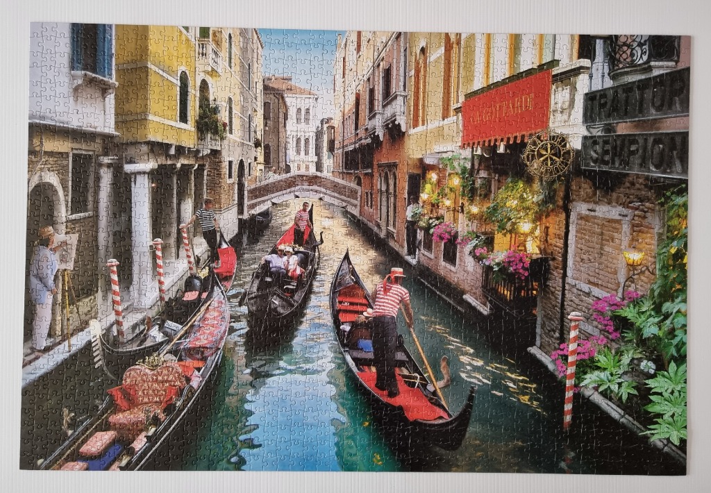 A painter captures a scenic Venetian canal filled with gondolas under a clear blue sky.