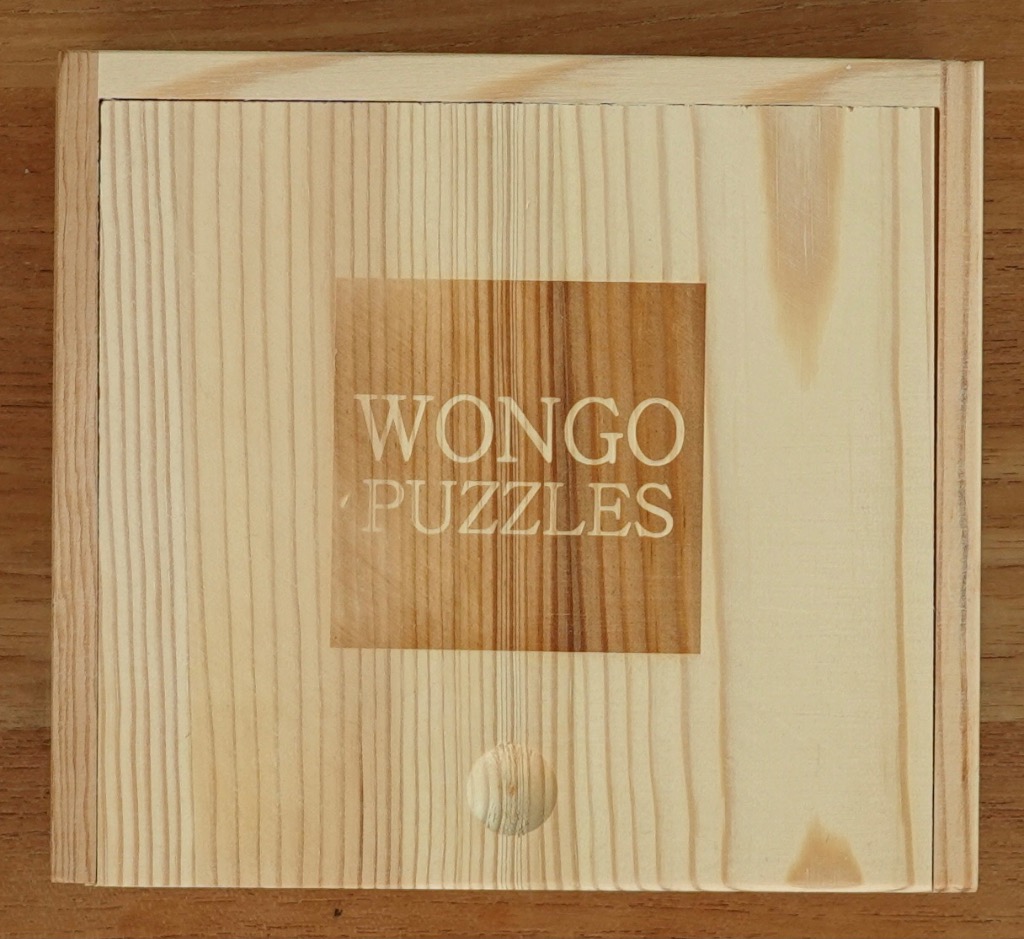 Light wooden square box with Wongo Puzzles logo embossed in the center.