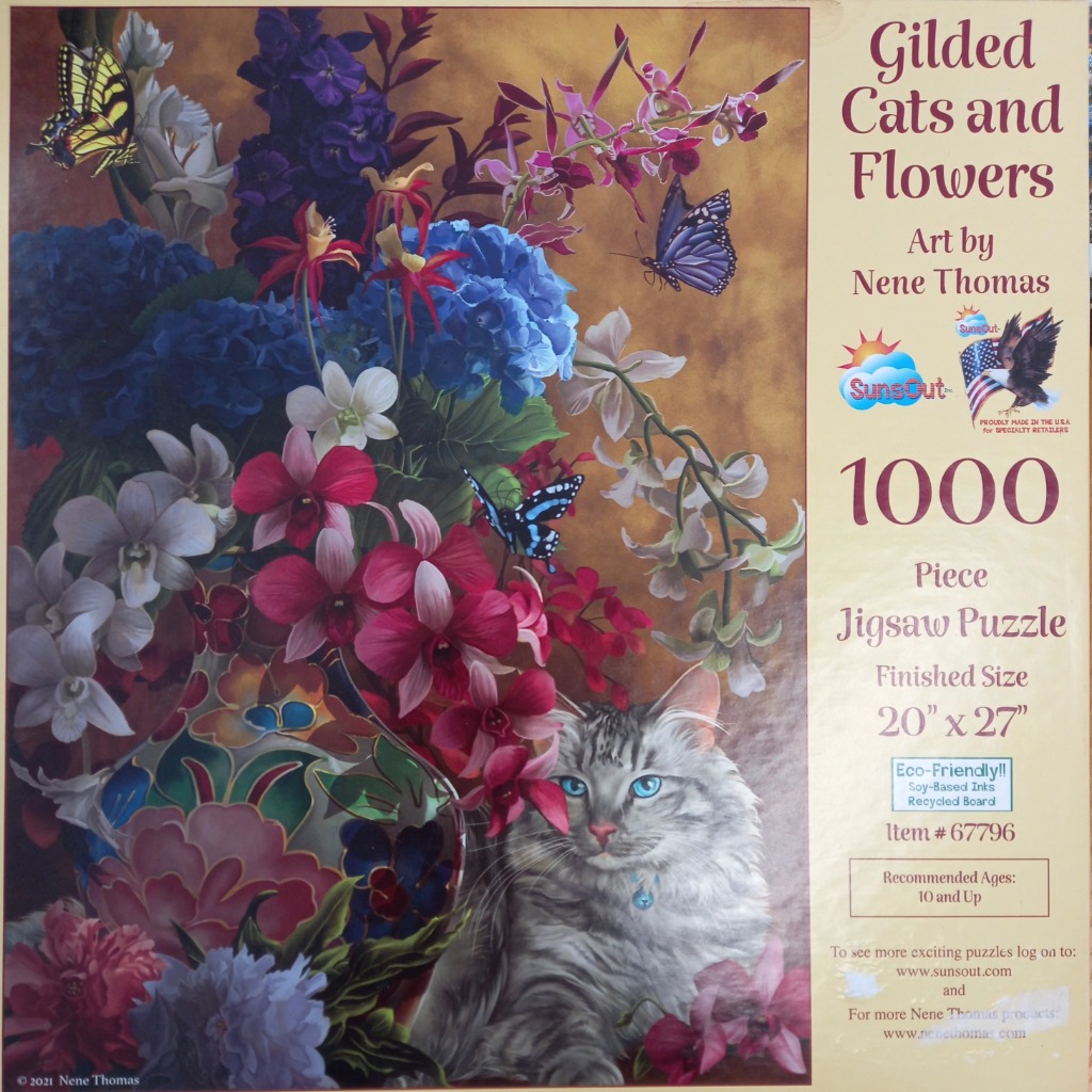 A silver-grey cat sits beside a decorative vase filled with vibrant blue and pink tropical flowers and butterflies.
