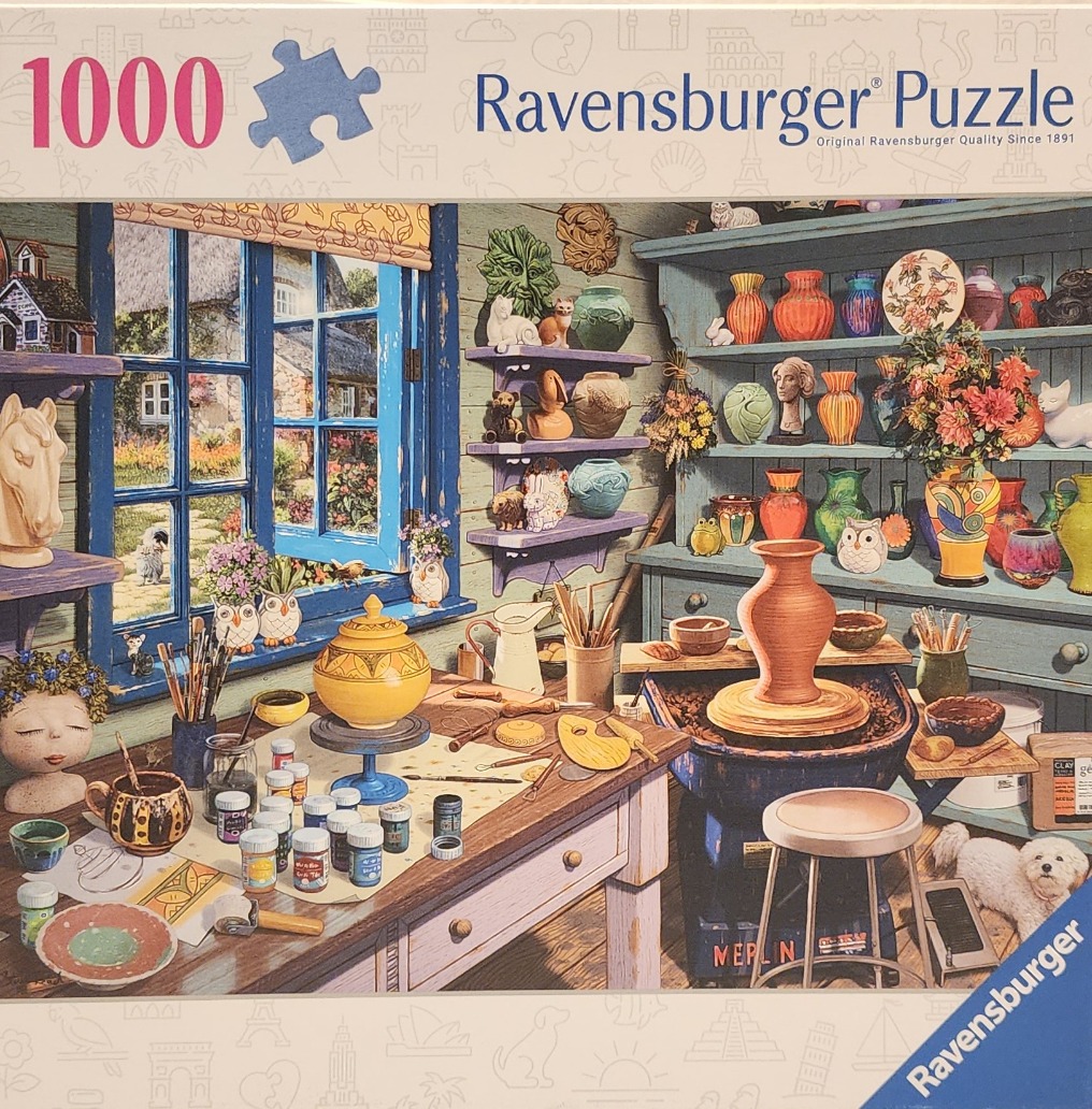 An artist's cozy pottery studio filled with ceramics, paints, a pottery wheel, and a view of a garden through a window.