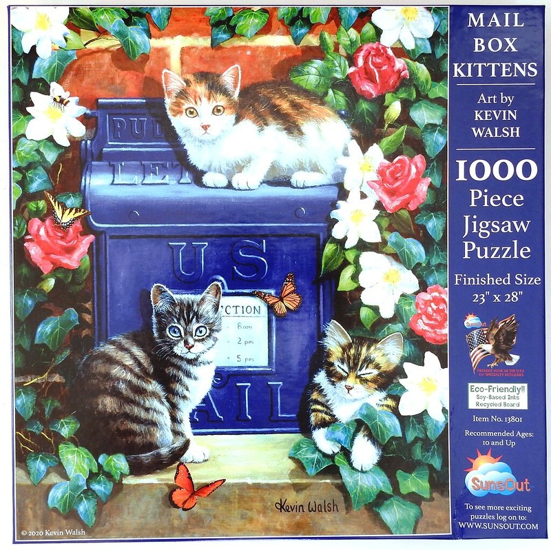 Three kittens sitting on and around a vintage blue US mailbox surrounded by red and white flowers and butterflies.
