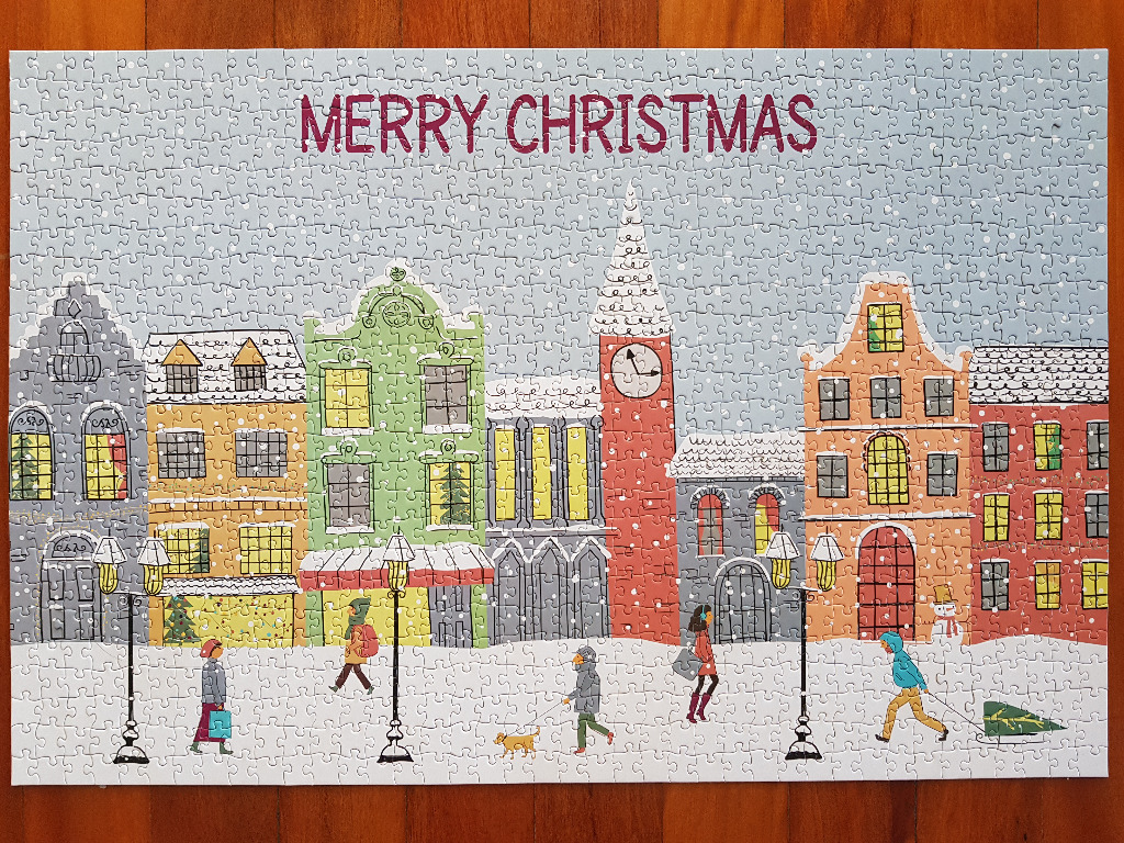 A whimsical illustration of a snowy town street at Christmas with people walking and festive buildings.