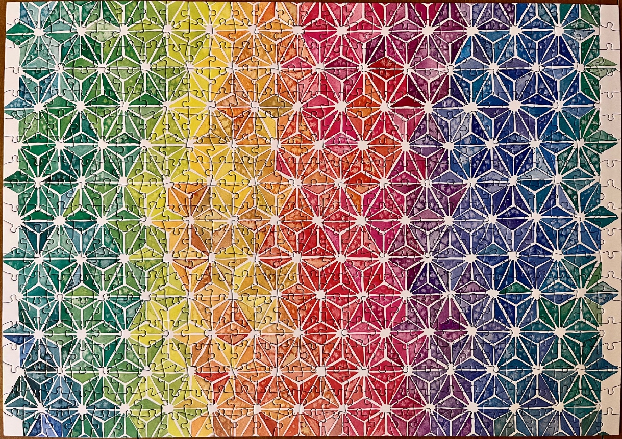 A geometric pattern of star-shaped tiles in a spectrum of colors from green to yellow, orange, red, and blue.