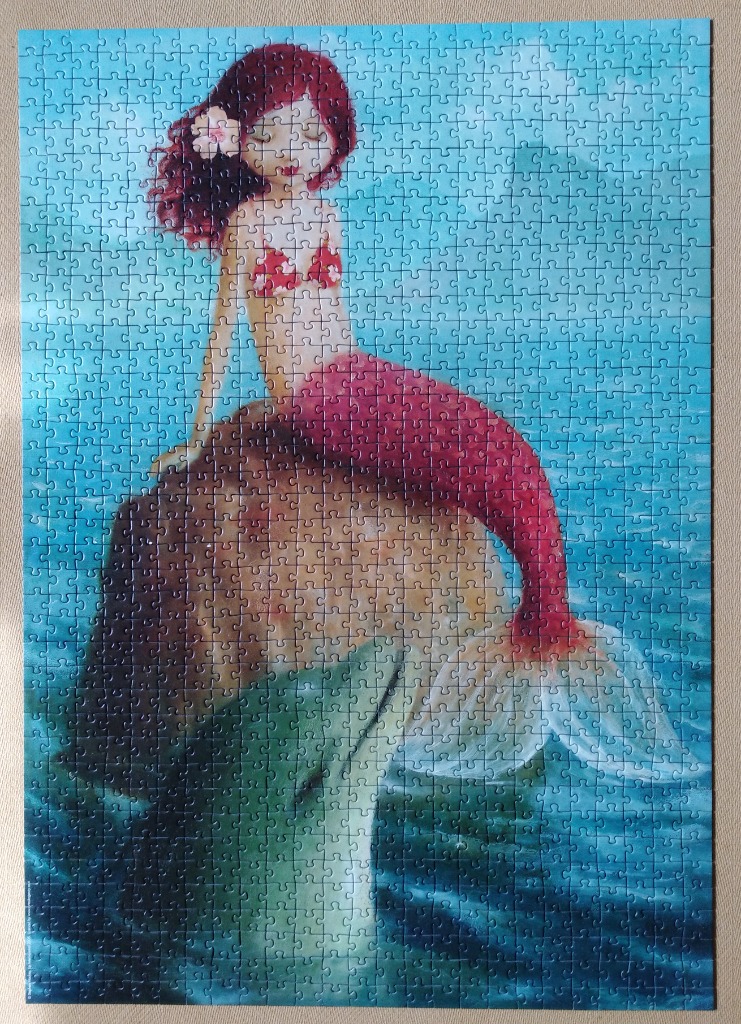 Illustration of a mermaid with red hair and a red tail sitting on a rock in the ocean