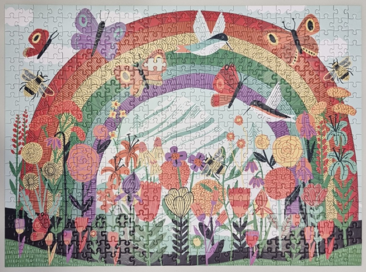 A whimsical illustration of a rainbow arching over a garden filled with flowers, butterflies, and hummingbirds.