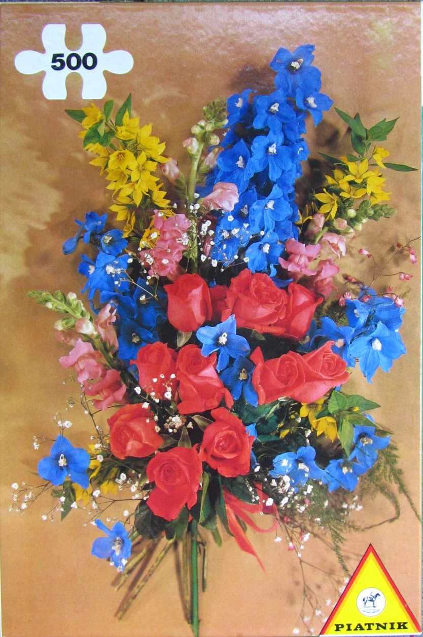 A lush bouquet of vibrant red roses, blue delphiniums, and yellow flowers against a tan background.