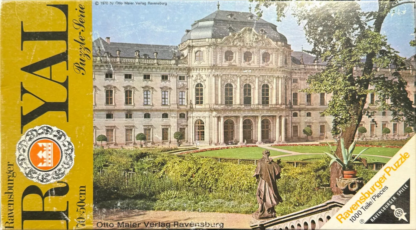A stately Baroque palace with a central dome, formal gardens, and a statue in the foreground.