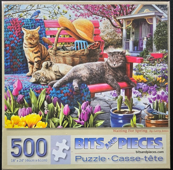Two cats lounging on a red bench in a vibrant spring garden with flowers and a wicker basket.