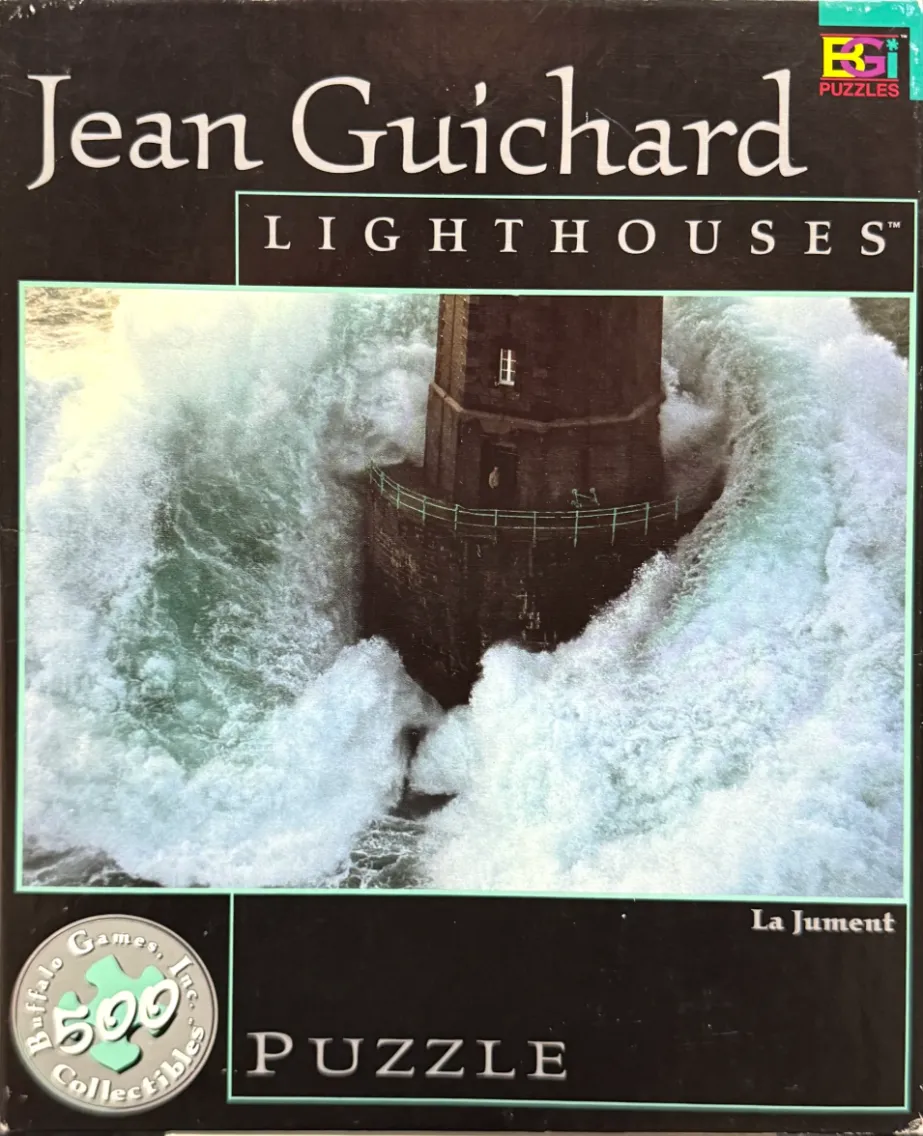 The La Jument lighthouse surrounded by a massive, crashing ocean wave.