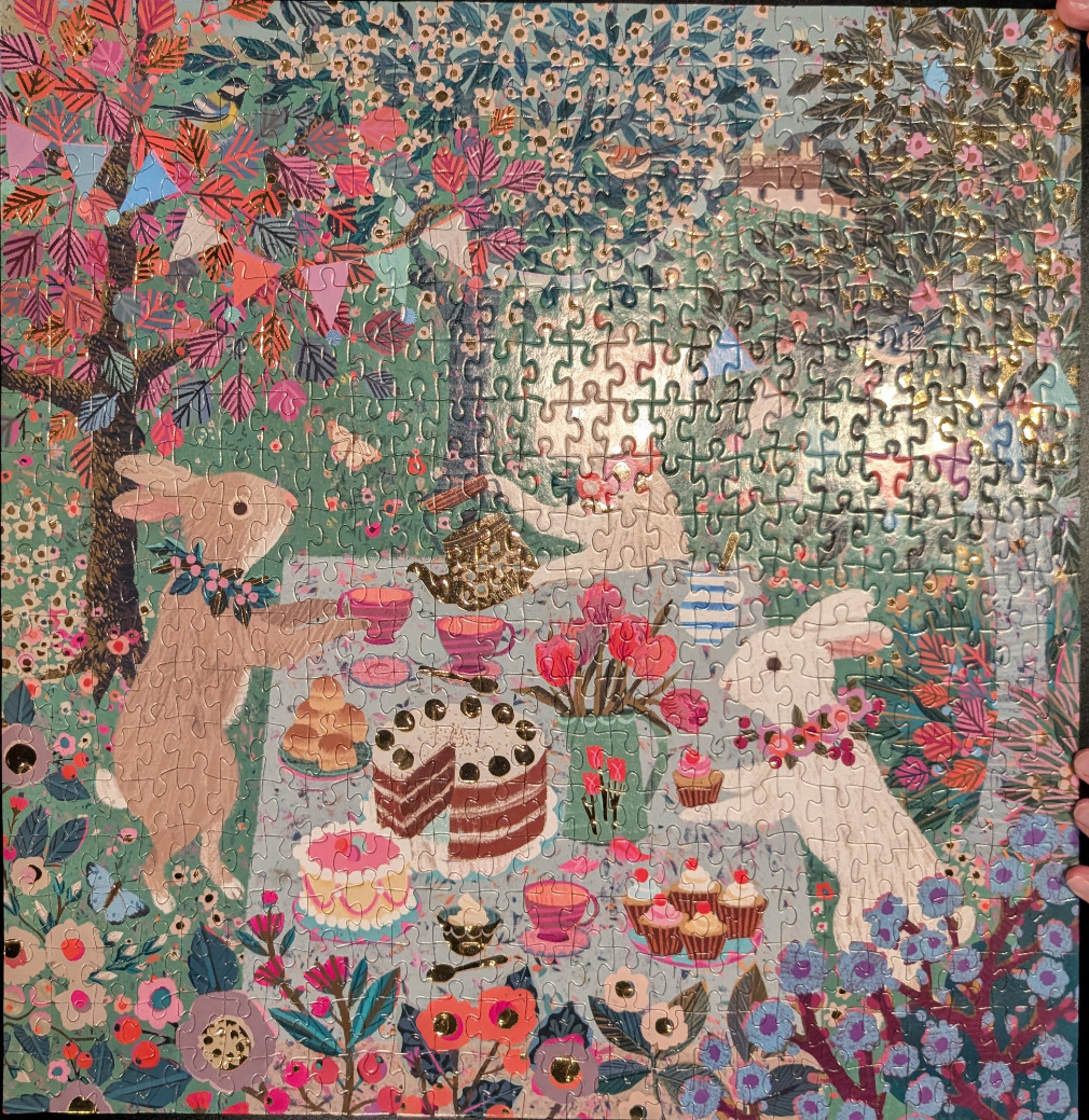 An illustration of two rabbits having a tea party in a lush, spring garden filled with flowers and gold accents.