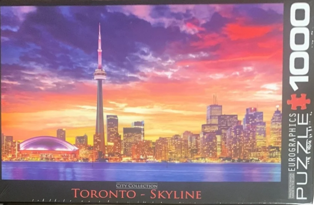 Toronto skyline at sunset with CN Tower, Rogers Centre, and city lights reflecting on the water.