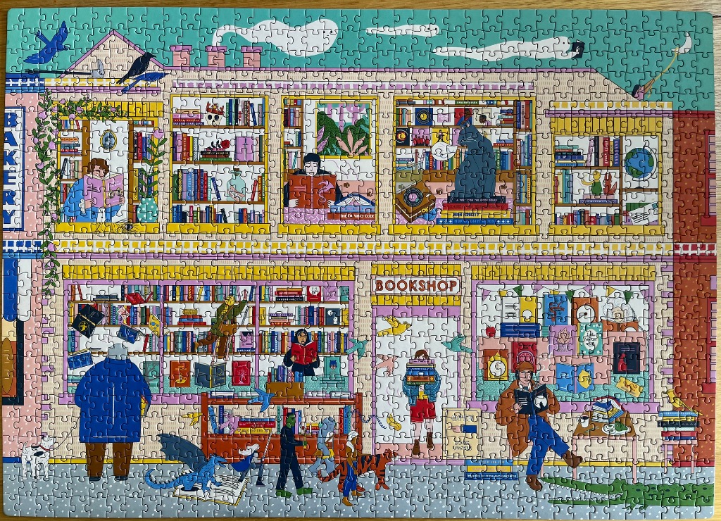 An illustrated, two-story bookshop building featuring multiple windows filled with bookshelves and people reading.