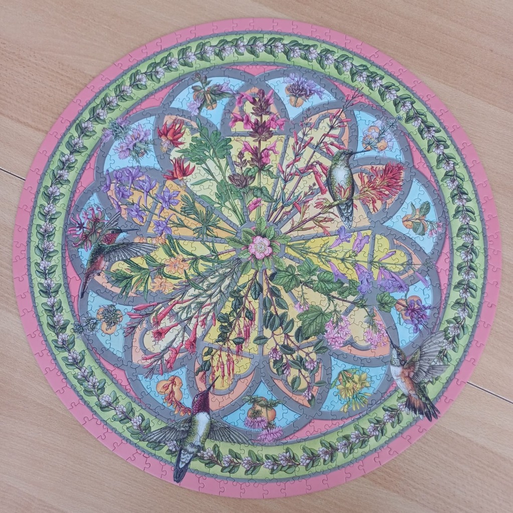 Circular illustration of three hummingbirds among wildflowers in a mandala pattern