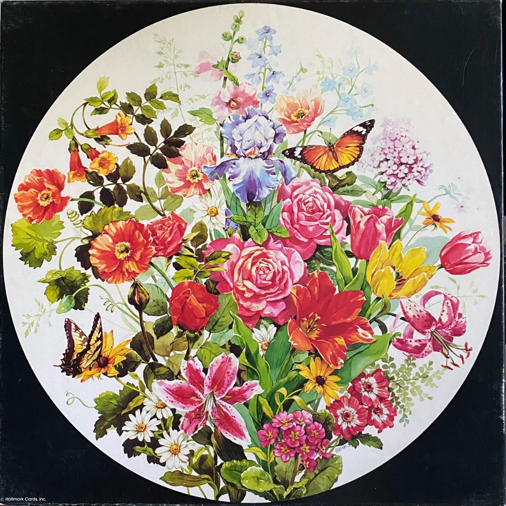 A circular floral arrangement featuring colorful spring and summer flowers and two butterflies.