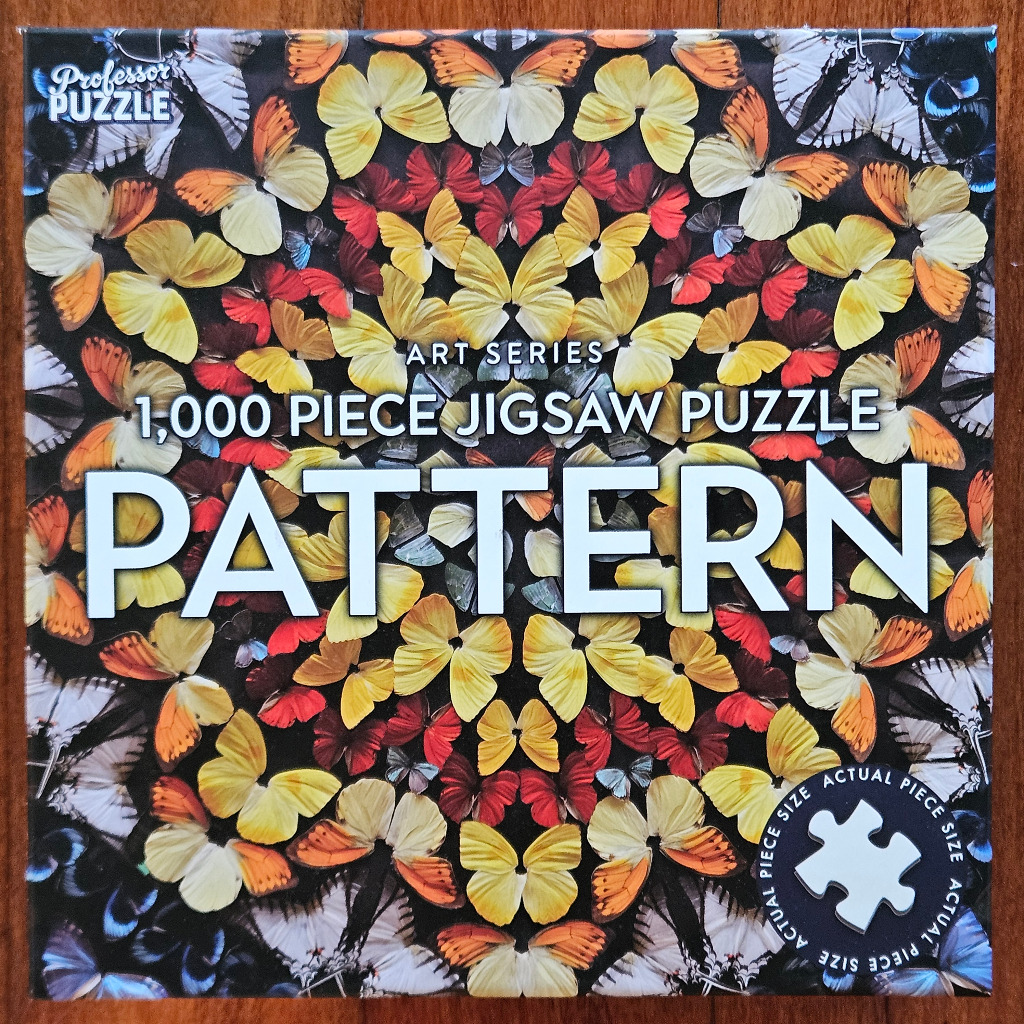 A kaleidoscope-style pattern of butterflies in shades of yellow, orange, red, and white against a black background.