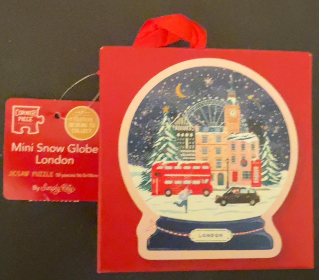 An illustration of a London scene inside a snow globe on a bright red background.