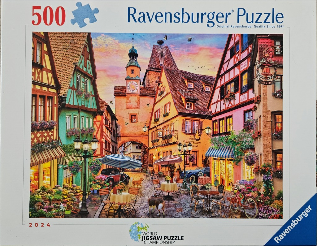 A charming European town square with timber-framed buildings and outdoor cafes under a sunset sky.