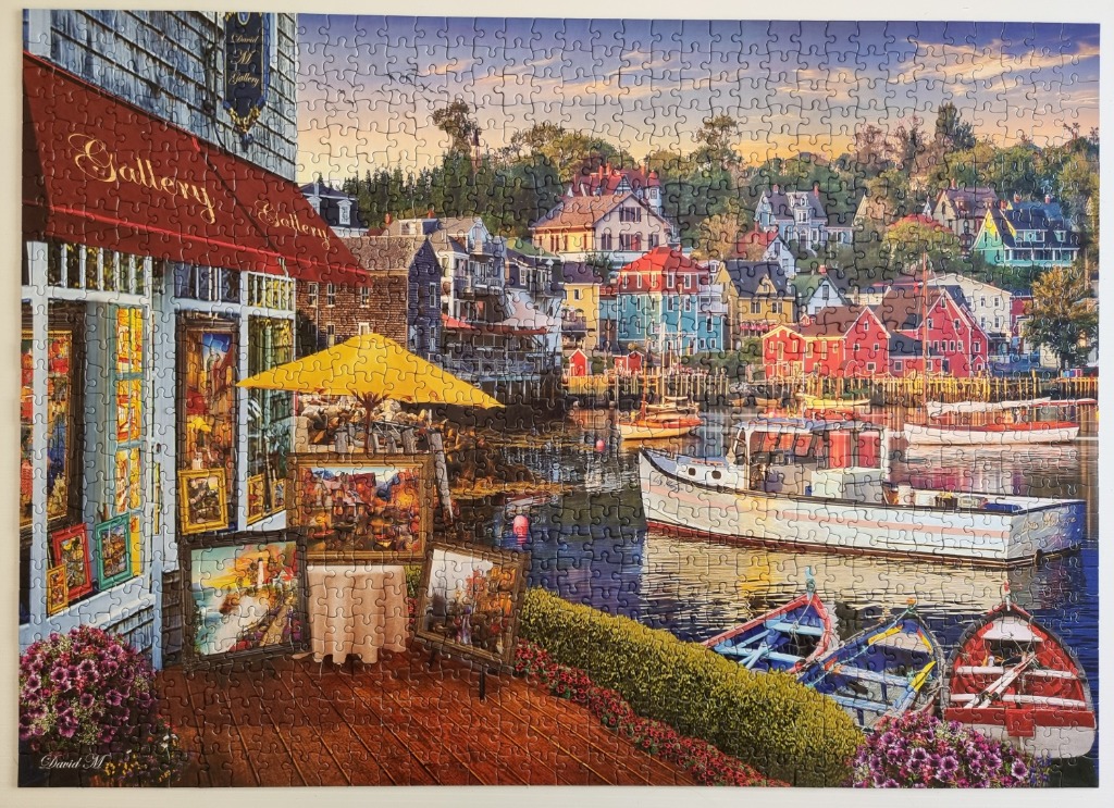 Coastal art gallery with a vibrant harbor scene and docked boats at sunset.