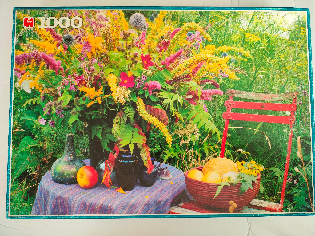 A lush summer garden scene featuring a table with flowers, fruit, and a red garden chair.