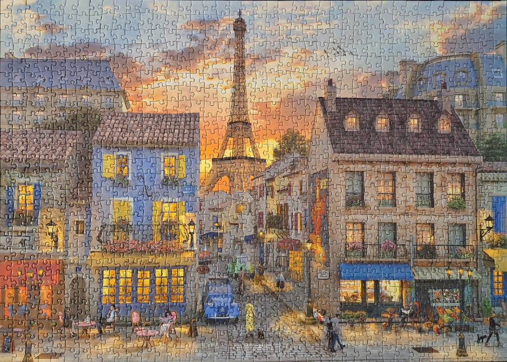 A warm, sunlit street scene in Paris featuring the Eiffel Tower in the distance between two historic buildings.