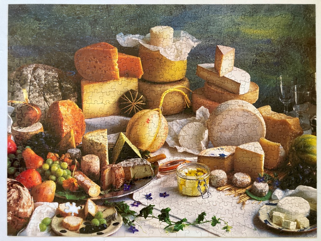 A rich, bountiful still life painting of a rustic cheese and fruit spread on a wooden table.