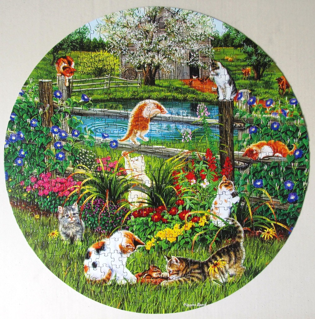 Circular illustration of multiple kittens playing in a lush garden with a pond and barn.