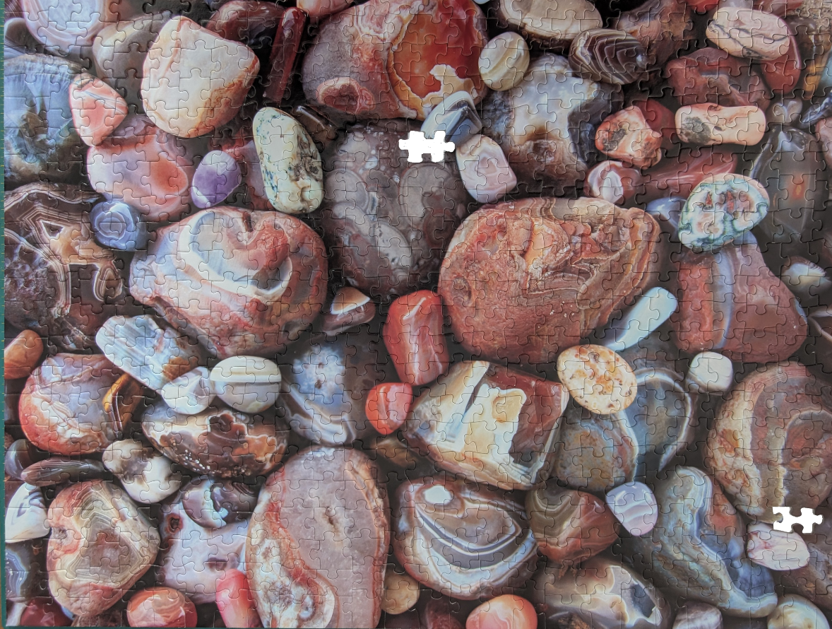 A close-up view of numerous polished river stones and banded agates of various sizes, colors, and textures.