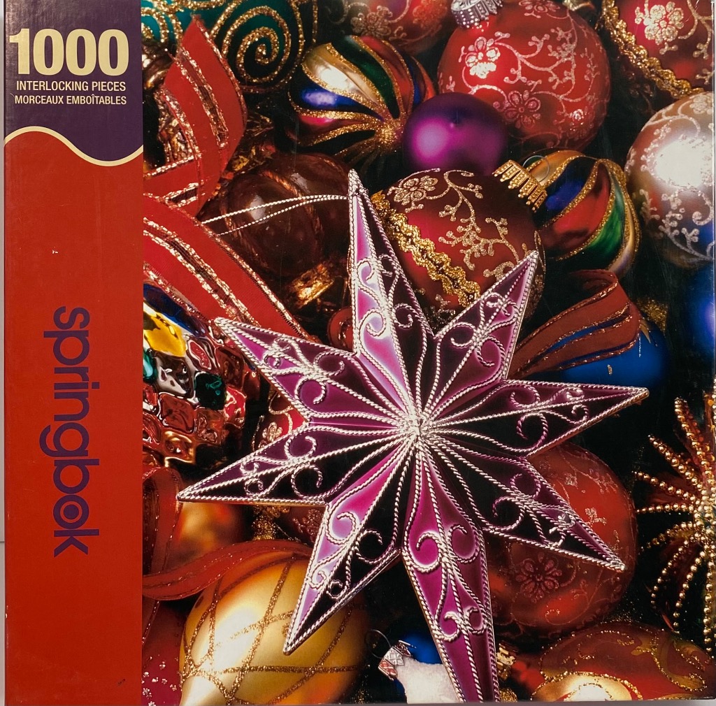 A close-up photograph of a collection of vibrant, sparkling Christmas ornaments featuring a large purple star.