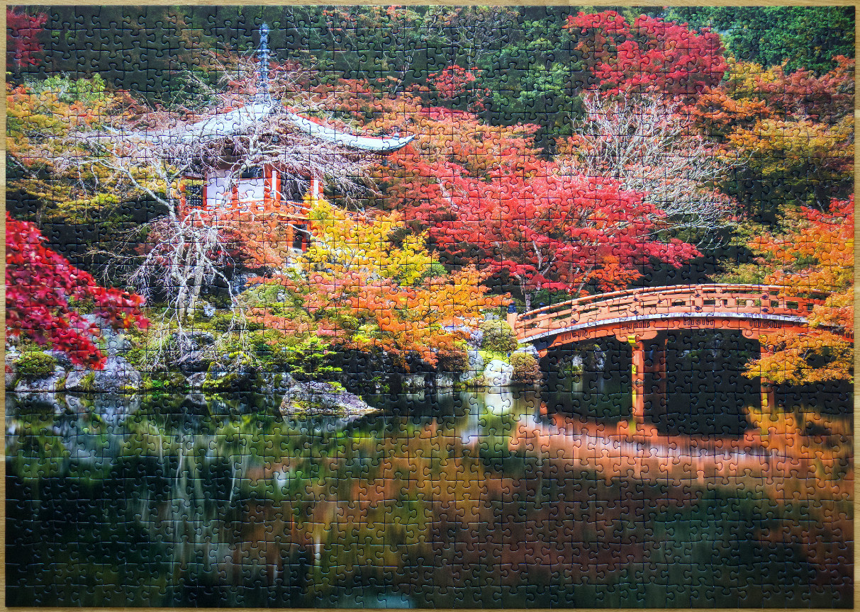 A traditional Japanese pagoda nestled in a vibrant autumn forest with a bridge over a reflective pond.