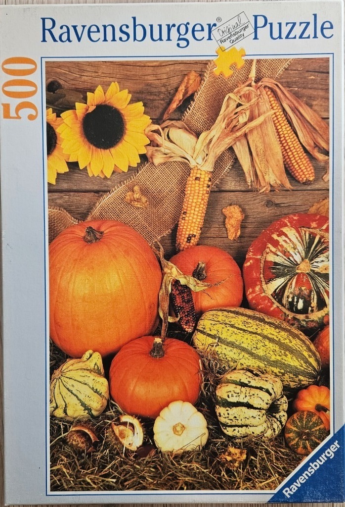 A fall-themed harvest still life featuring pumpkins, gourds, sunflowers, and dried corn against a rustic wooden backdrop.