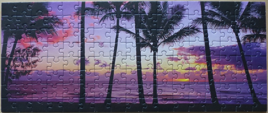 A panoramic tropical sunset scene silhouetting palm trees against a purple and orange sky.
