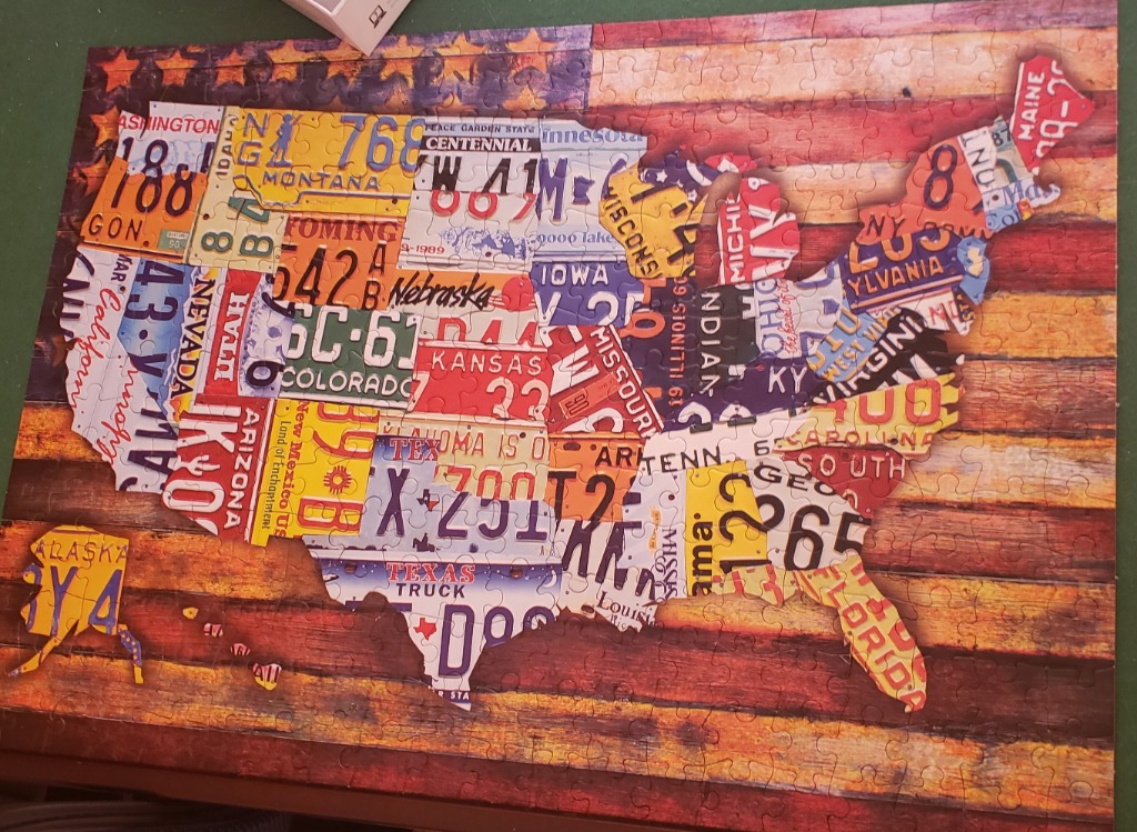 A map of the United States constructed from vintage license plates against a rustic wooden background.