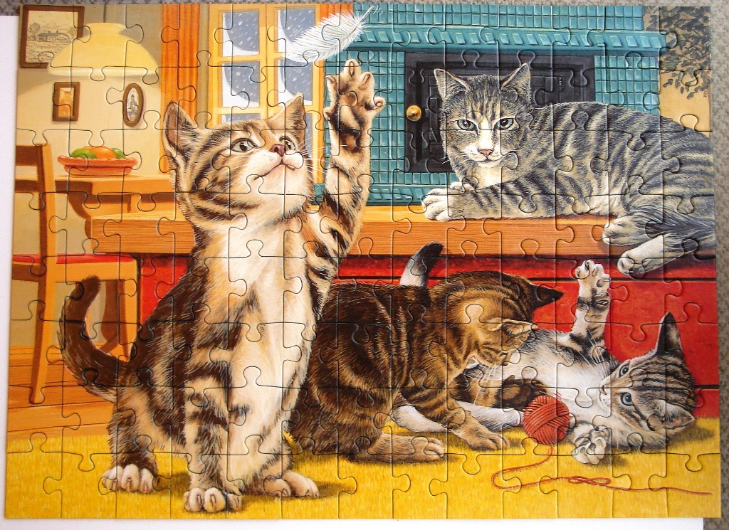 Three tabby kittens playing in a cozy, sunlit room with a tiled fireplace