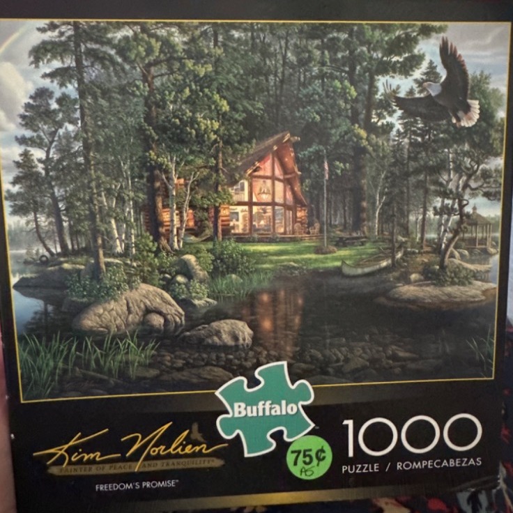 A log cabin nestled in a forest by a lake with a bald eagle flying above.