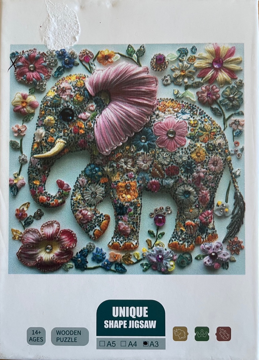 An elephant decorated with intricate embroidery and beaded flowers against a pale blue background.