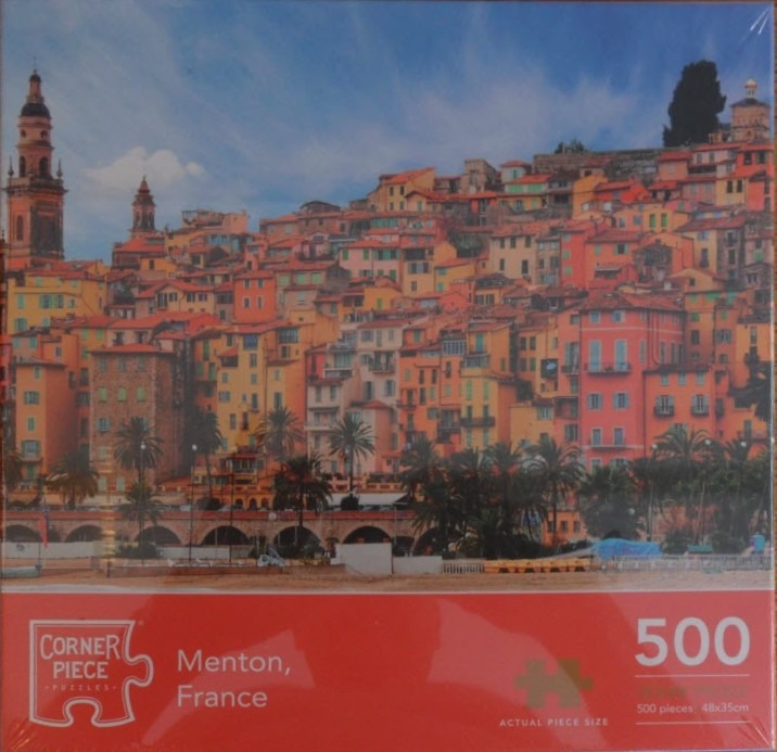 Panoramic view of the colorful hillside town of Menton, France, against a bright blue sky.