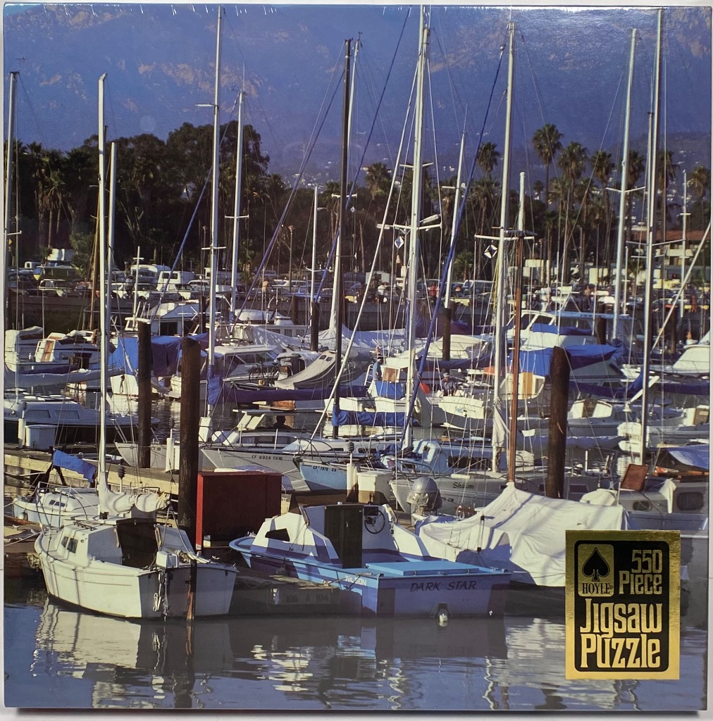 Boats moored at a marina with palm trees and a mountain backdrop